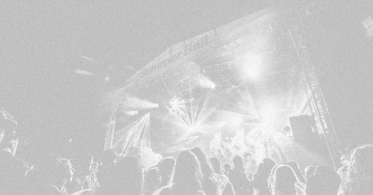 A photograph of the Summer Ball stage with a crowd of people silhouetted by the production lights