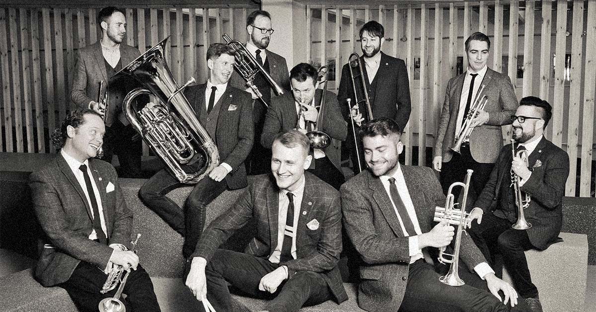 A group of men wearing suits and smiling, holding brass instruments