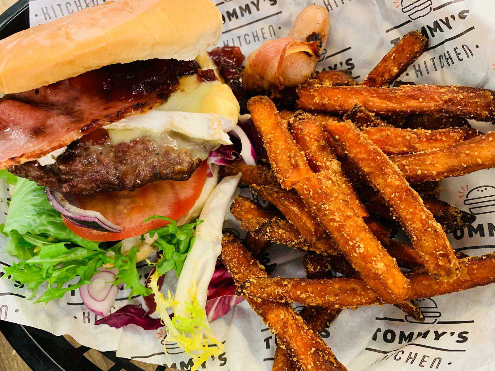 image of a Christmas special beef burger with bacon and brie, served with sweet potato fries